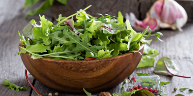 Fresh mixed salad greens in wooden bowl